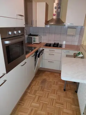 a kitchen with white appliances and a wooden floor at Apartma Kaj in Kaja in Maribor