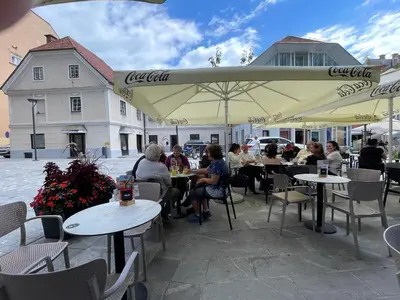 a group of people sitting at tables under an umbrella at Celje Luxury Apartment in Celje
