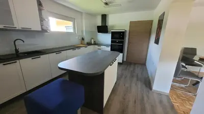 a kitchen with a counter and a blue stool at Orange house Šempeter in Šempeter v Savinjski Dolini