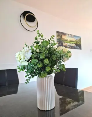a white vase with green and white flowers on a table at Orange house Šempeter in Šempeter v Savinjski Dolini