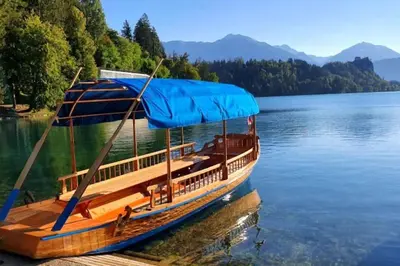 a wooden boat with a blue canopy on a lake at Apartma Kenda in Bled
