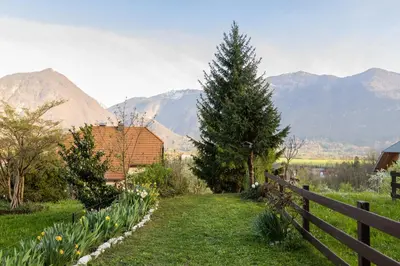 a garden with a fence and mountains in the background at Apartment Lilija in Bovec