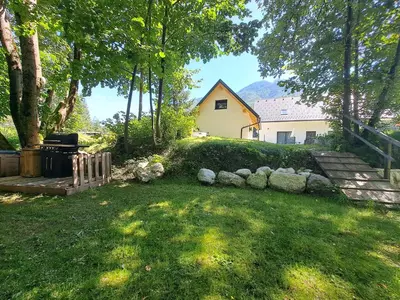 a backyard with a stone wall and a house at Riverside Apartma 2, Kranjska Gora in Kranjska Gora