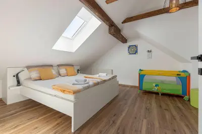 a white bedroom with a bed and a tv at Holiday House Žalec in Griže