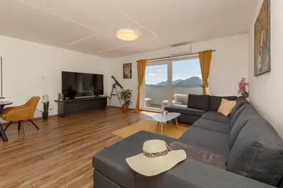 a living room with a gray couch and a television at Holiday House Žalec in Griže