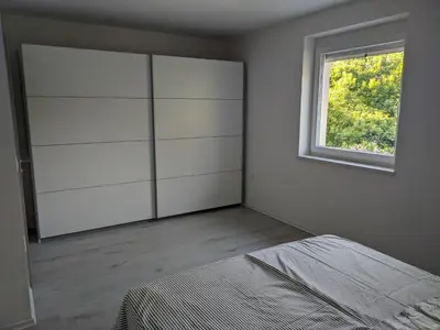 a white bedroom with a bed and a window at Počitniška hiša Hum in Kojsko