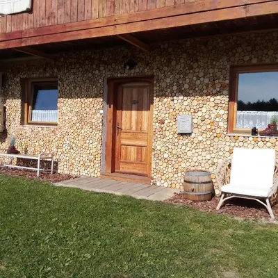 a stone house with a wooden door and a white chair at Apartmaji BORŠTNER in Vransko