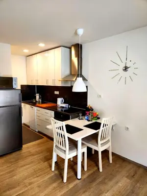 a kitchen with a table and chairs and a clock on the wall at Studio Apartma V8 in Maribor