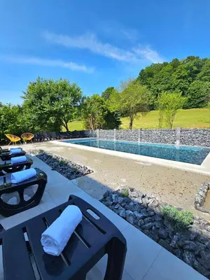 a patio with lounge chairs and a swimming pool at VILA LISJAK - Apartments in Podčetrtek