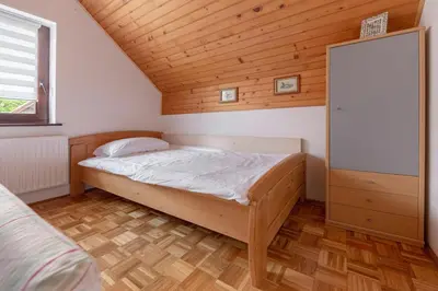 a small bedroom with a bed and a wooden ceiling at Apartma Mikelj in Bohinj