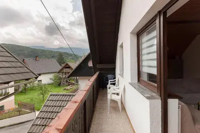 a balcony with a table and a chair on a building at Apartma Mikelj in Bohinj