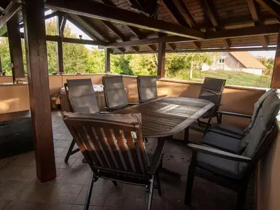 a wooden table and chairs on a porch at Holiday house Zarja - with sauna and hot tub in Bizeljsko