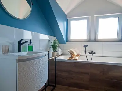 a bathroom with a tub and a sink and two windows at Holiday house Zarja - with sauna and hot tub in Bizeljsko