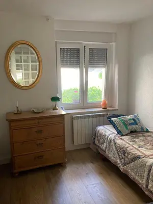 a bedroom with a bed and a dresser and two windows at Apartma Kresnička in Kobarid