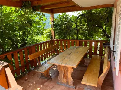a wooden picnic table on a deck with trees at Apartma Kresnička in Kobarid