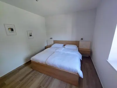 a small bedroom with a bed with white sheets at Prenočišča v Kraški Hiši in Komen