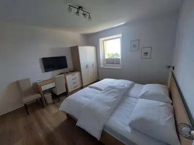 a bedroom with a bed and a desk and a television at Prenočišča v Kraški Hiši in Komen