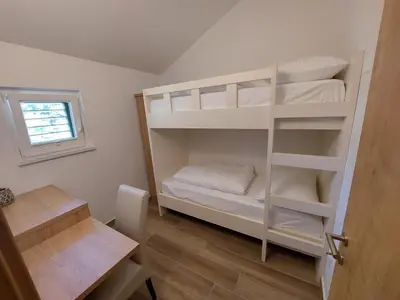 a room with a bunk bed with white bunk beds at Prenočišča v Kraški Hiši in Komen