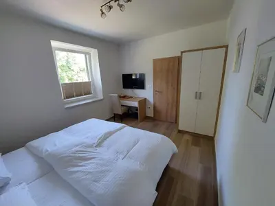 a bedroom with a white bed and a desk at Prenočišča v Kraški Hiši in Komen