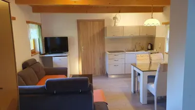 a living room with a couch and a table and a kitchen at Hiška ob gozdu in Polzela