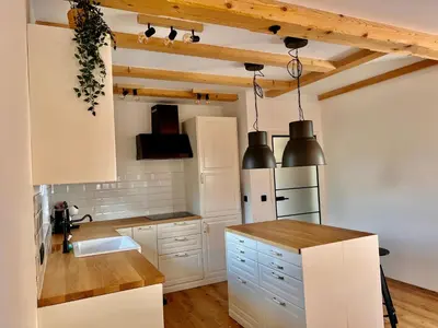 a kitchen with white cabinets and wooden ceilings at Vila Milan in Bled