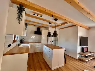 a kitchen with white cabinets and wooden ceilings at Vila Milan in Bled