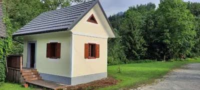 a small house with a black roof on a yard at Apartma Povlč in Poljane nad Škofjo Loko