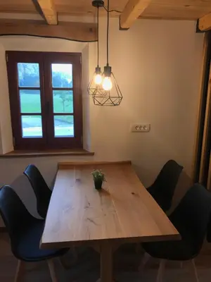 a wooden table with chairs in a room with a window at Apartma Povlč in Poljane nad Škofjo Loko