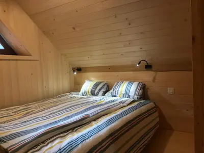 a bed in a wooden cabin with two pillows at Apartma Povlč in Poljane nad Škofjo Loko