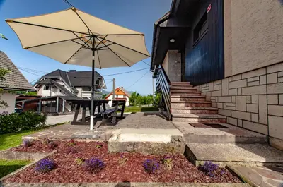 a patio with an umbrella and a table with purple flowers at Apartment Vita in Bled