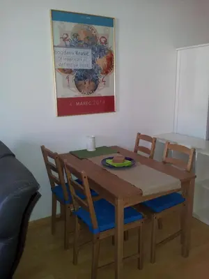a wooden table and chairs with a poster on the wall at Studio Ian 1 in Ljubljana