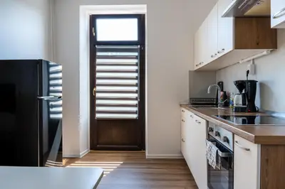 a kitchen with white cabinets and a black refrigerator at Apartment Ivana Krško in Krško
