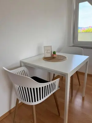 a white table and a chair with a picture on it at Green House Apartment in Pivka