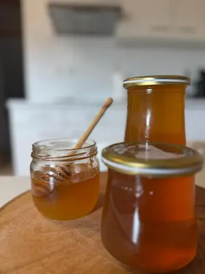 two jars of honey on a wooden table at Green House Apartment in Pivka