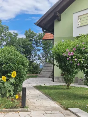 a walkway leading to a green building with flowers at Green House Apartment in Pivka