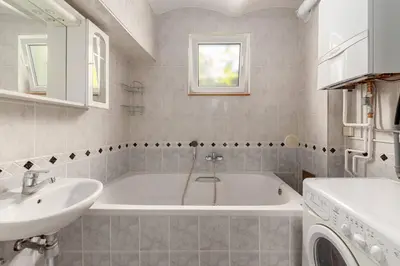 a bathroom with a tub and a sink and a washing machine at Vila ART in Ljubljana