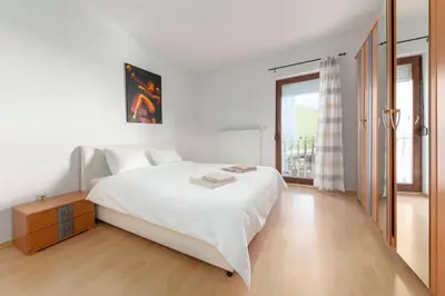 a white bedroom with a large bed and a window at Vila ART in Ljubljana