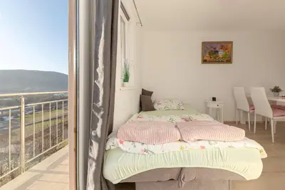 a bedroom with a bed and a balcony with a view at Zidanica med Trtami in Dvor