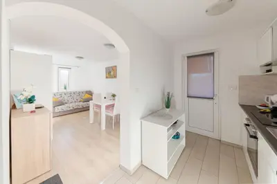 a white kitchen and living room with a table at Zidanica med Trtami in Dvor