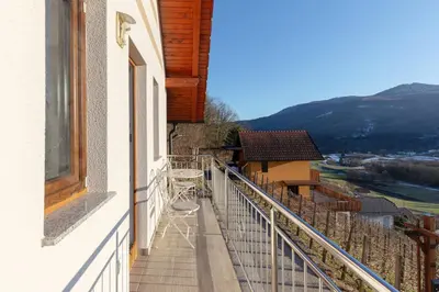 a balcony with a table and chairs on a building at Zidanica med Trtami in Dvor
