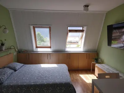 a bedroom with a bed and two windows at Apartma Luca, Bovec in Bovec