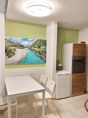 a kitchen with a white table and a painting of a river at Apartma Luca, Bovec in Bovec