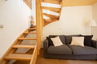 a living room with a couch and a wooden staircase at GUTA in Bled