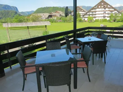 a patio with tables and chairs and a view of a field at Guest House Golja in Bled
