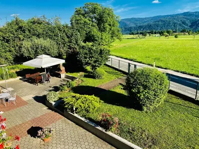a garden with a table and an umbrella at Guest House Golja in Bled