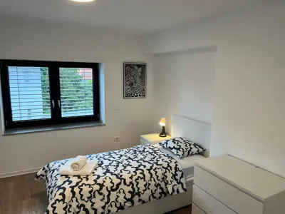 a white bedroom with a bed and a window at Villa Kovačeva apartments, Marice Kovačeve 15, app 1, free parking in Ljubljana