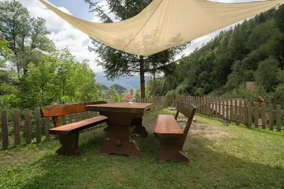 a picnic table and bench in a yard with a tent at Olga & Ludvik country apartment in Podbrdo