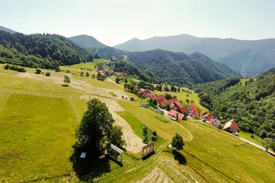 an aerial view of a green field with houses and mountains at Olga & Ludvik country apartment in Podbrdo