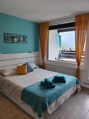 a bedroom with a bed with blue walls and a window at Apartma Eda, Bovec in Bovec