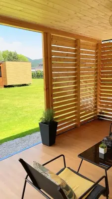 a patio with wooden shutters and a table and chairs at Premium mobile home Eden in Velenje